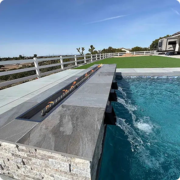 Luxury swimming pool with sleek built-in fire feature and stone tile design in a spacious backyard