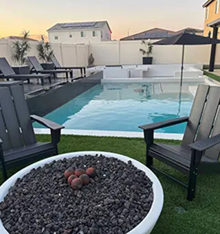 Contemporary backyard with swimming pool, lounge chairs, and round firepit with seating at sunset
